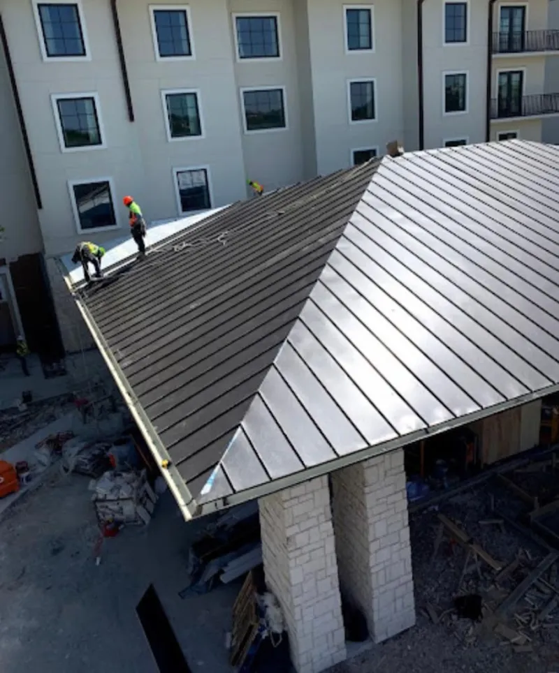 Crew installing standing seam metal roof panels on a commercial project in New Boston